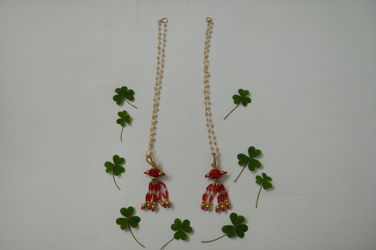 Pair of red and gold beaded earrings on a white background