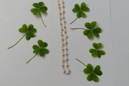 Gold necklace with green clover leaves on a white background
