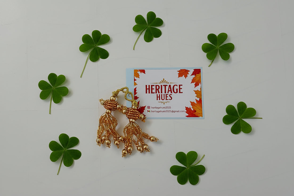 Gold earrings on a 'Heritage Hues' branded card with autumn leaves design.