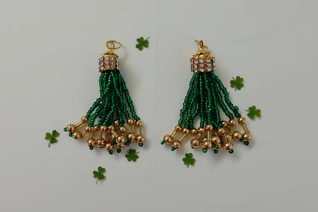 Pair of green beaded earrings with gold accents on a light gray background
