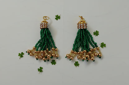 Pair of green beaded earrings with gold accents on a light gray background