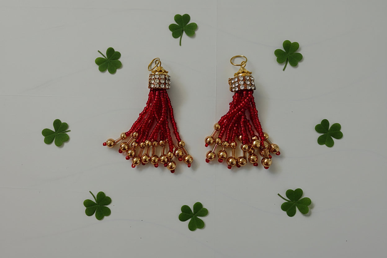 Two red tassels with gold beads on a gray background
