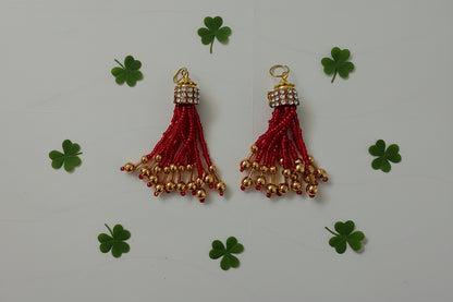 Two red tassels with gold beads on a gray background