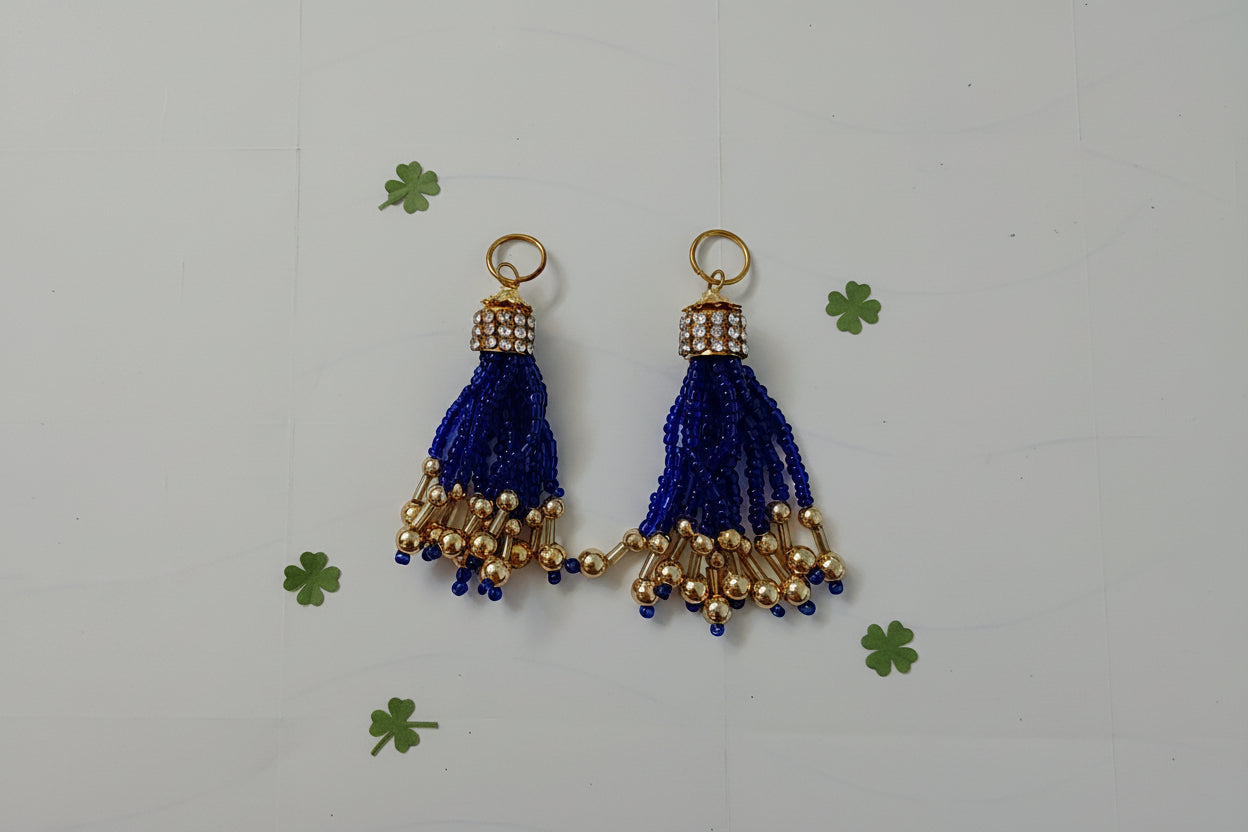 Two blue tassel charms with gold accents on a white background