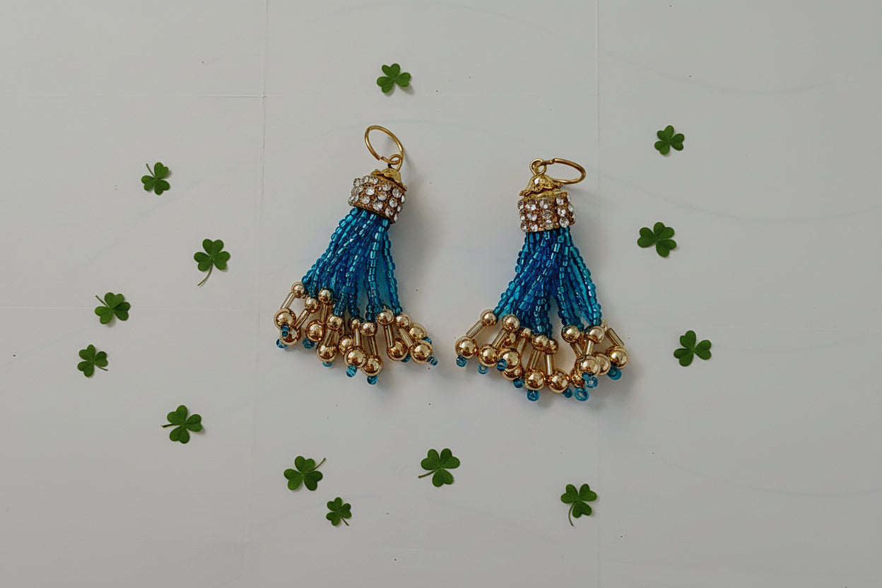 Pair of blue and gold tassel earrings on a light gray background
