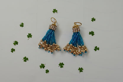 Pair of blue and gold tassel earrings on a light gray background