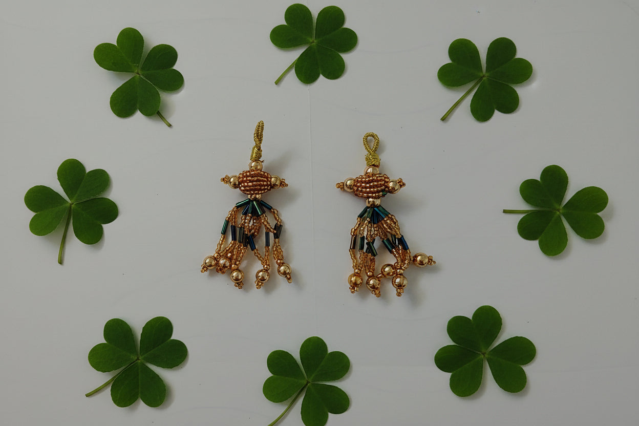 Pair of gold earrings with green and blue accents on a gray background