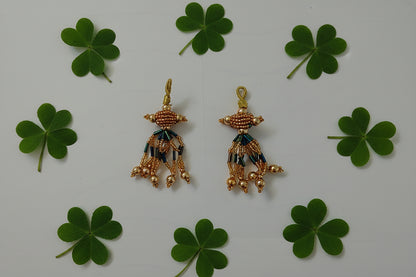 Pair of gold earrings with green and blue accents on a gray background