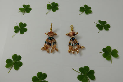 Pair of gold earrings with green and blue accents on a gray background