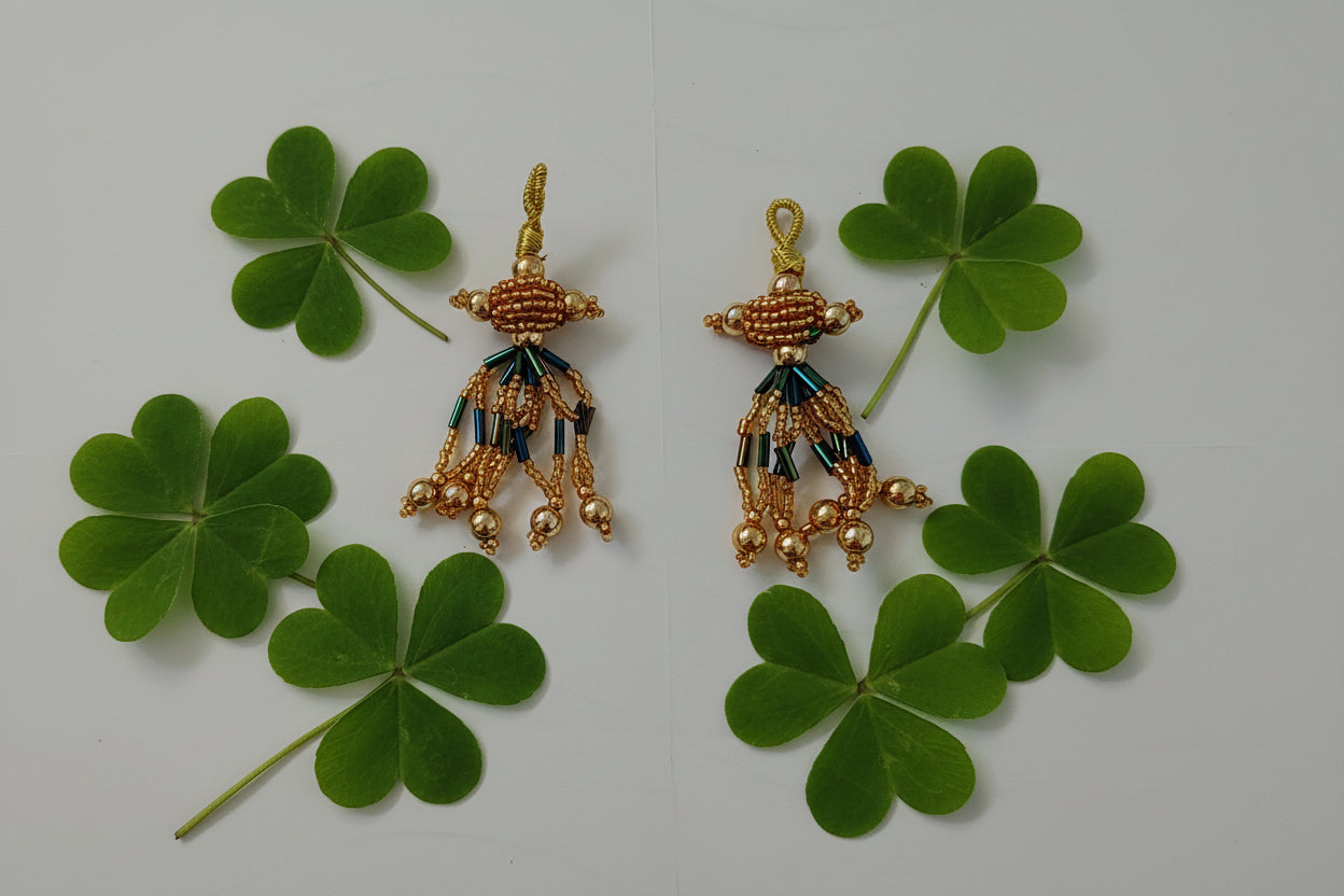 Pair of gold and green beaded earrings on a gray background