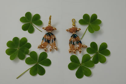 Pair of gold and green beaded earrings on a gray background