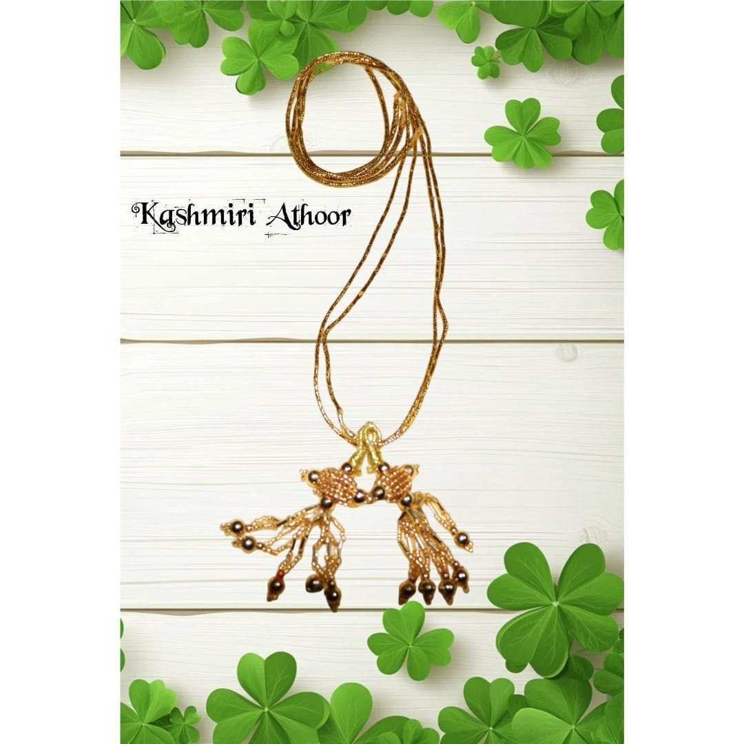 Gold necklace with pendant on a white background with green leaves