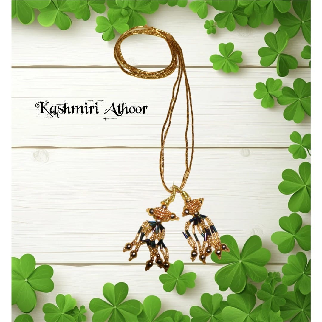Gold necklace with pendants on a white background with green shamrock leaves