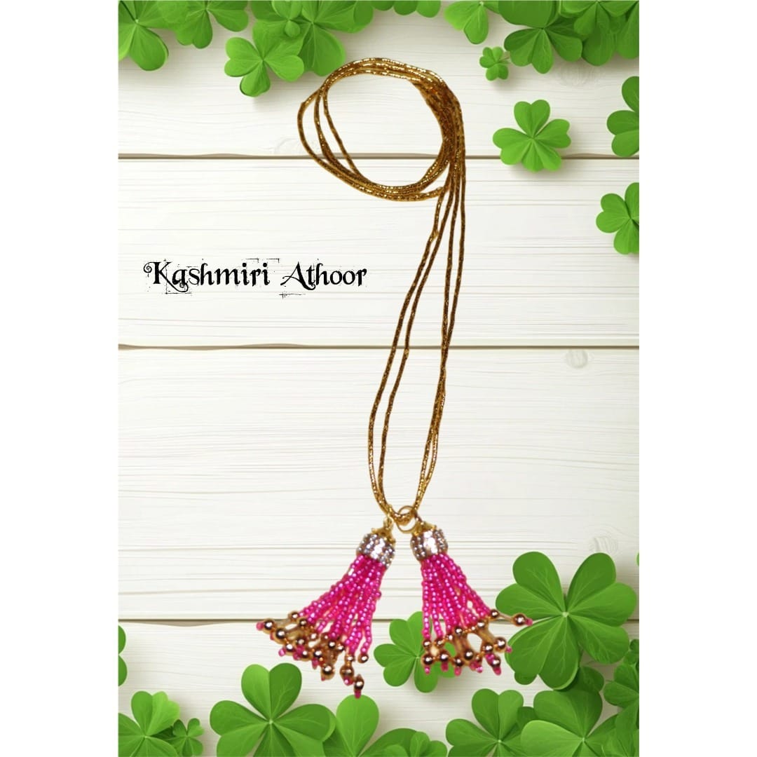 Gold necklace with pink pendants on a white background with green leaves