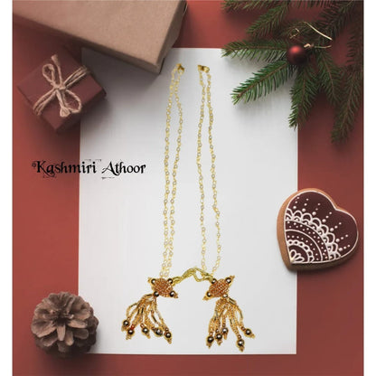 Gold necklace on a white card with decorative elements on a red background